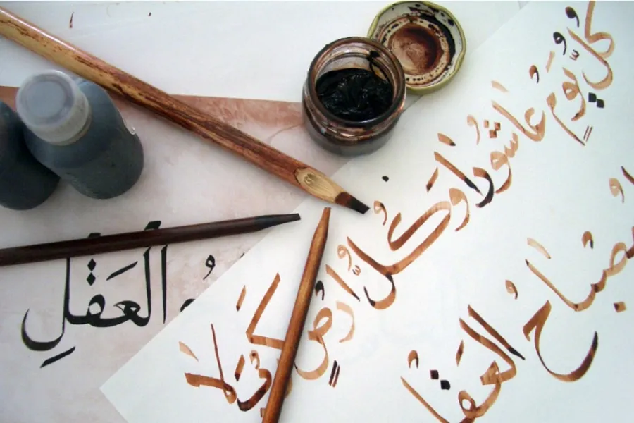 Arabic calligraphy on paper with brushes and ink